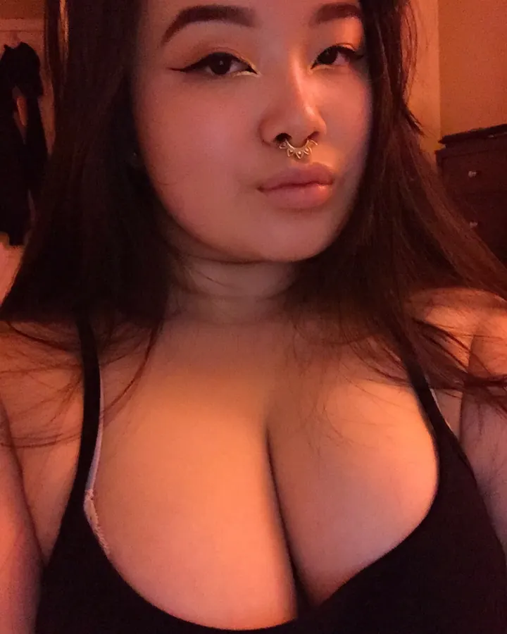 Femme trans asiatique, en lingerie noire, posant sur un lit avec des cheveux longs
